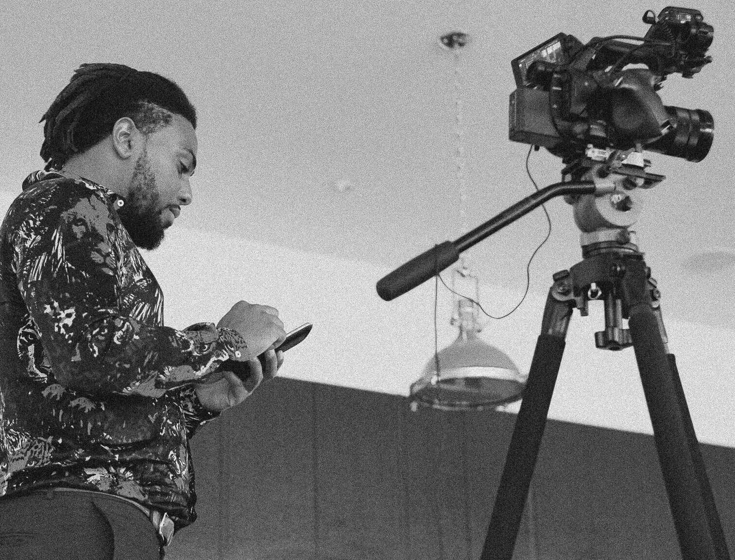 Corey checking his phone beside a camera rig in the video studio