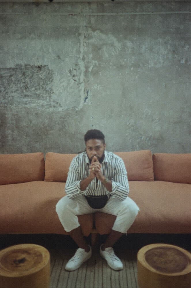 Corey sitting still on a sofa, hands together, deep in thought