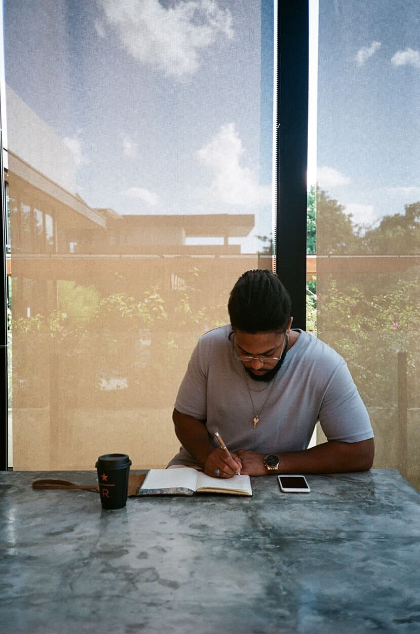 Corey writing in a notebook at an open-air table