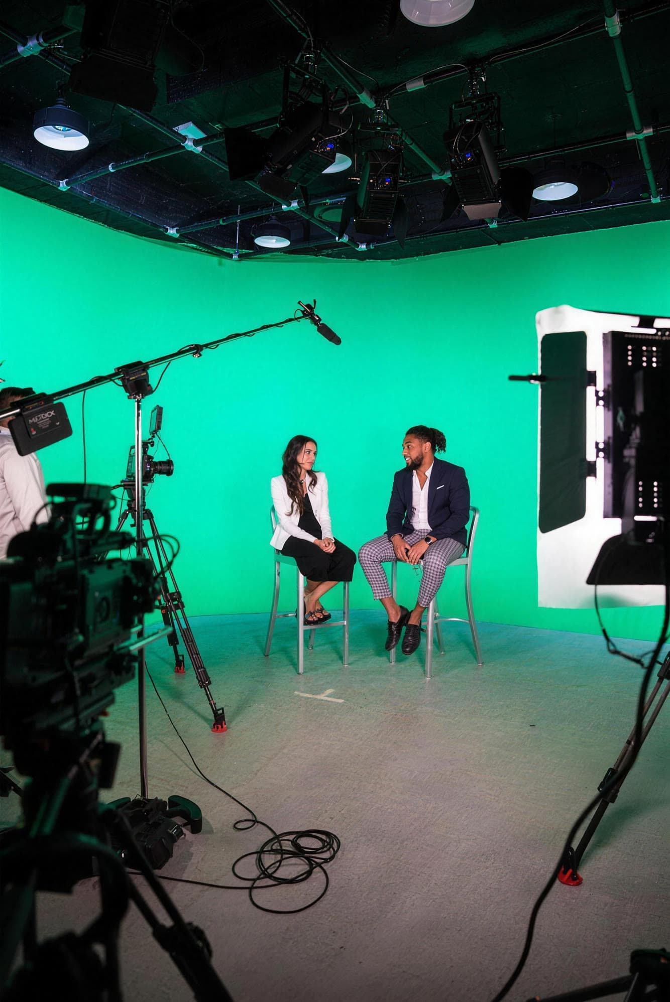 Corey on set in a green screen studio, in conversation with a guest